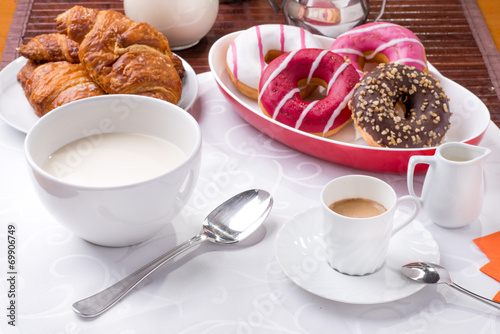 Prima colazione con donuts, brioches, latte e caffè photo