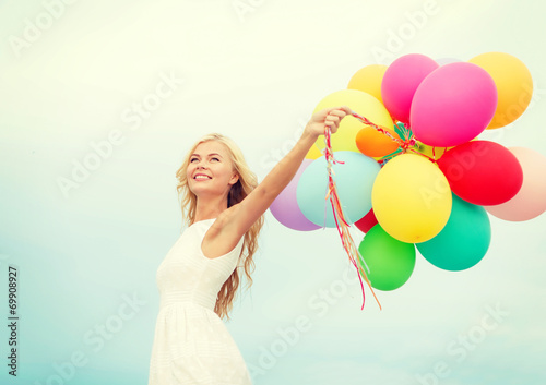 smiling woman with colorful balloons outside © Syda Productions