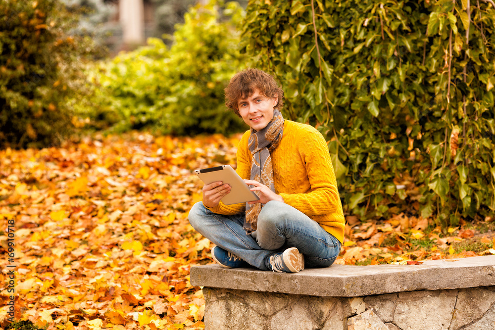 Fototapeta premium young man with tablet outdoor at autumn