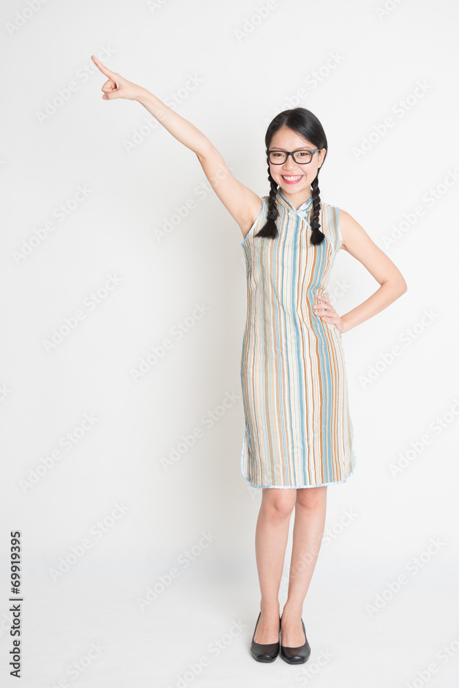 Full length Asian Chinese girl pointing on blank space Full length Asian Chinese girl pointing on blank space