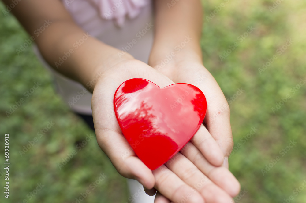 Hand of a girl holding a toy heart Hand of a girl holding a toy heart