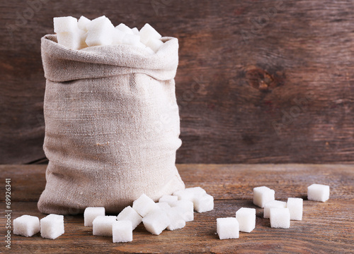 Refined sugar in bag on wooden background