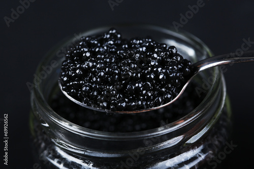 Jar of black caviar and spoon with black caviar