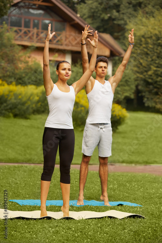 Yoga Exercise. Young couple meditating in fitness club