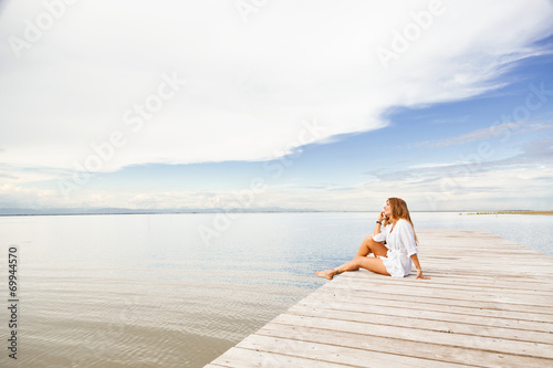 smiling Young woman talking on the phone on a pier © guerrieroale