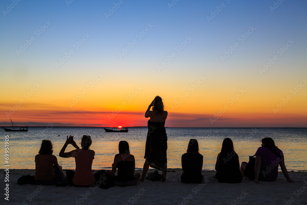 Women sitting on the beach watching the sunset