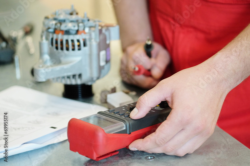 Hands of mechanic restores a generator