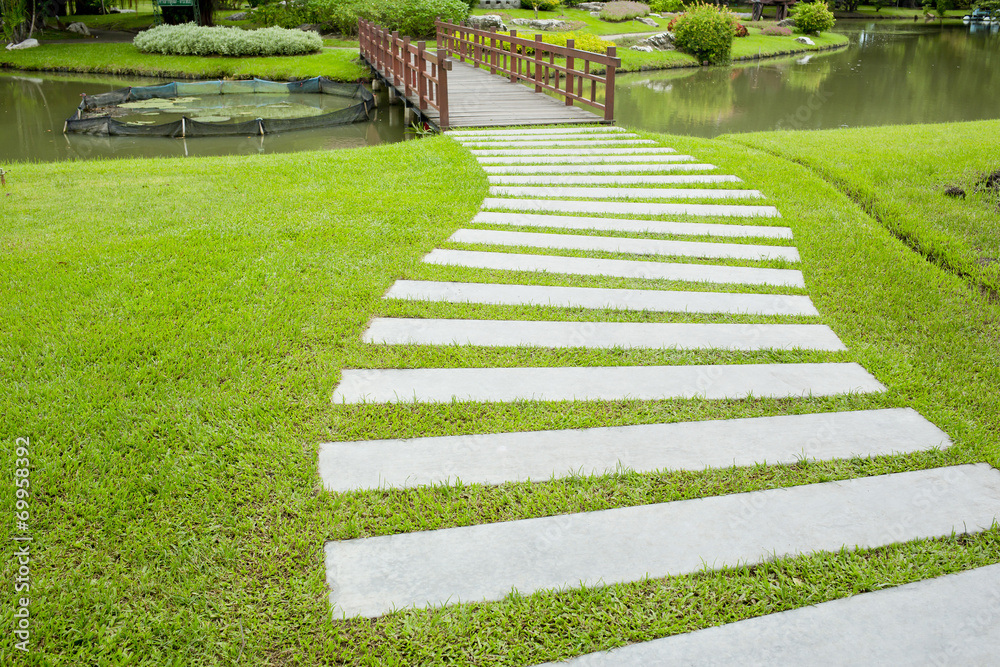 The Stone block walk path in the park with green grass backgroun The Stone block walk path in the park with green grass backgroun