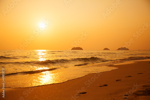 Beautiful sunset above the sea. Footprints in the sand.