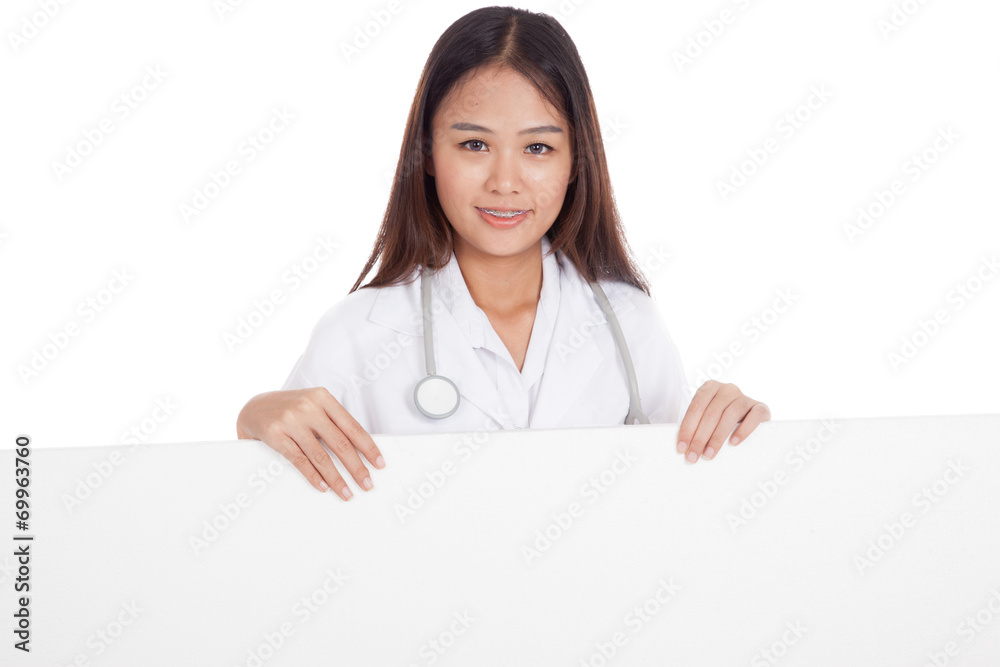 Young Asian female doctor standing behind blank white billboard