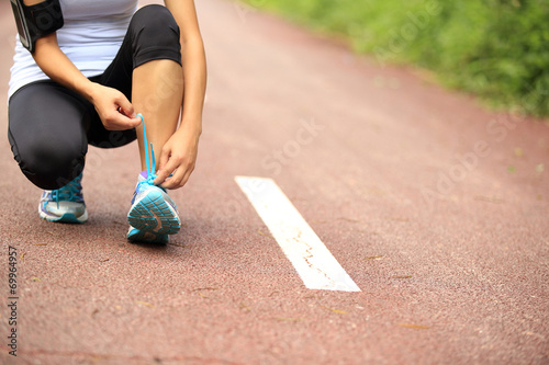 woman runner tying shoelace on trail