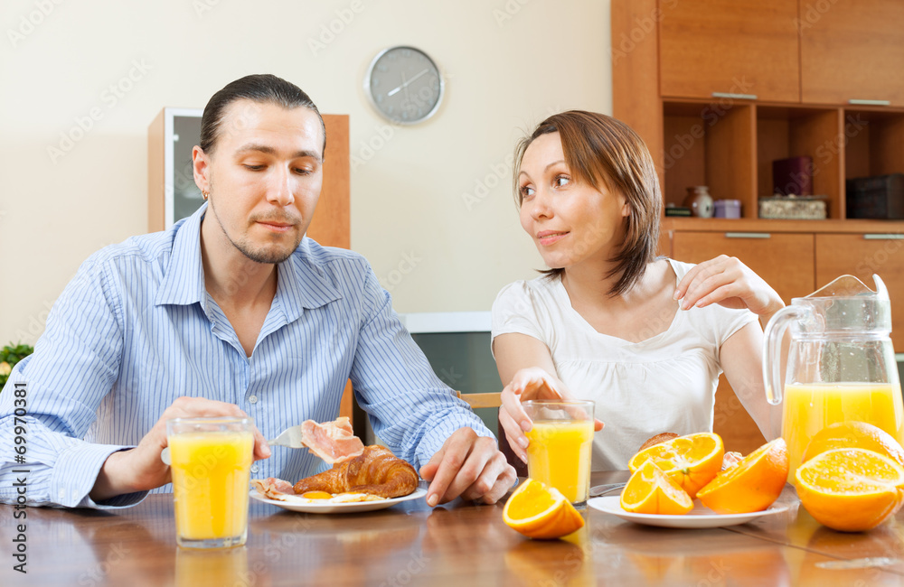  couple having breakfast with scrambled eggs and oranges