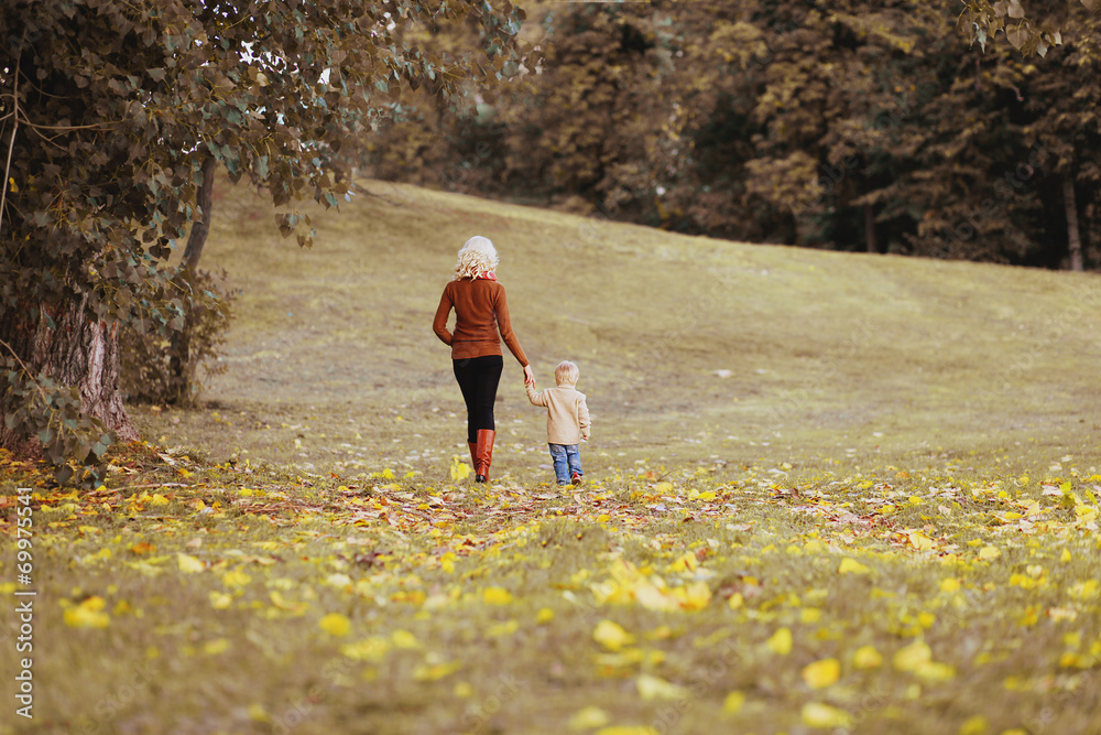 Fototapeta premium Silhouette of mom and baby in autumn day, happy family walking
