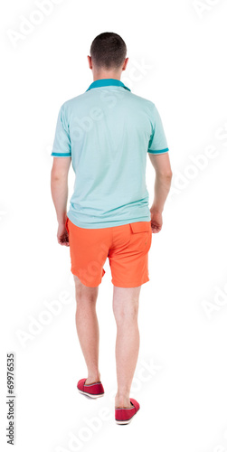 Back view of going handsome man in shorts. walking young guy