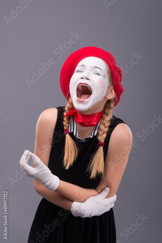 Portrait of female mime in red head and with white face isolated