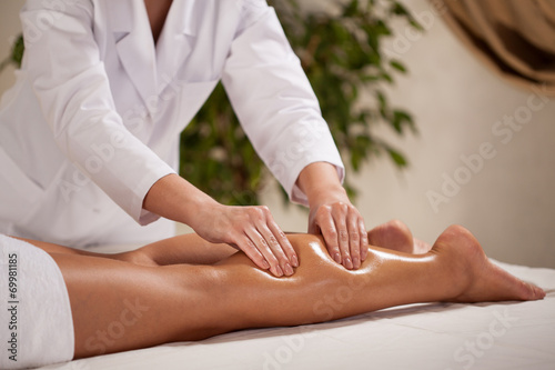 Masseur massaging woman's calf