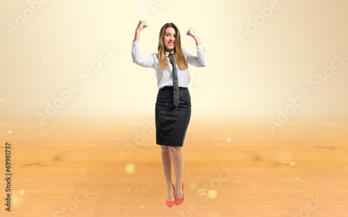 Young businesswoman winning over ocher background