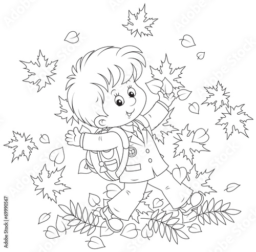 Joyful schoolboy throws up autumnal leaves