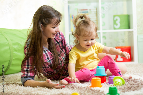 child girl and her mother playing together with toys