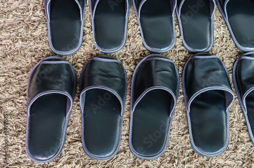 Foto row of black slippers on carpet