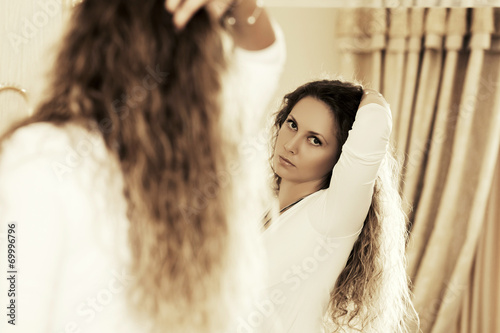 Beautiful fashion woman looking in the bedroom mirror