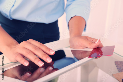 Woman using digital tablet and holding credit card in her hand.