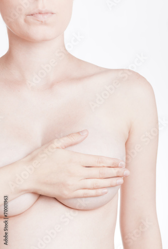 adult woman examining her breast for lumps or breast cancer
