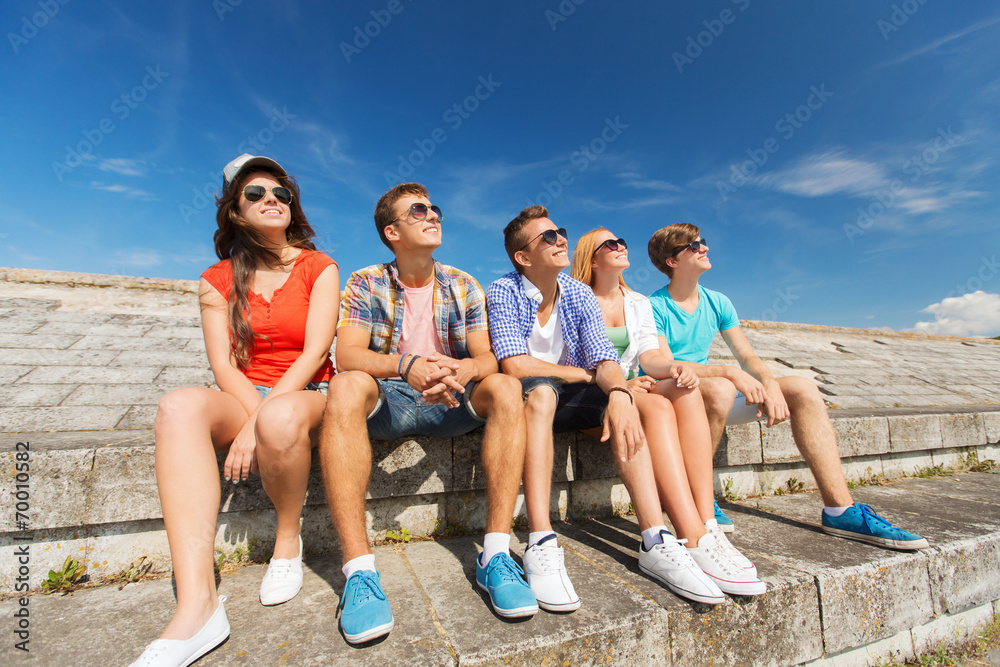 group of smiling friends sitting on city street group of smiling friends sitting on city street