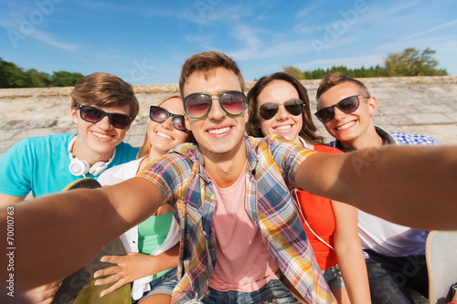 group of smiling friends making selfie outdoors