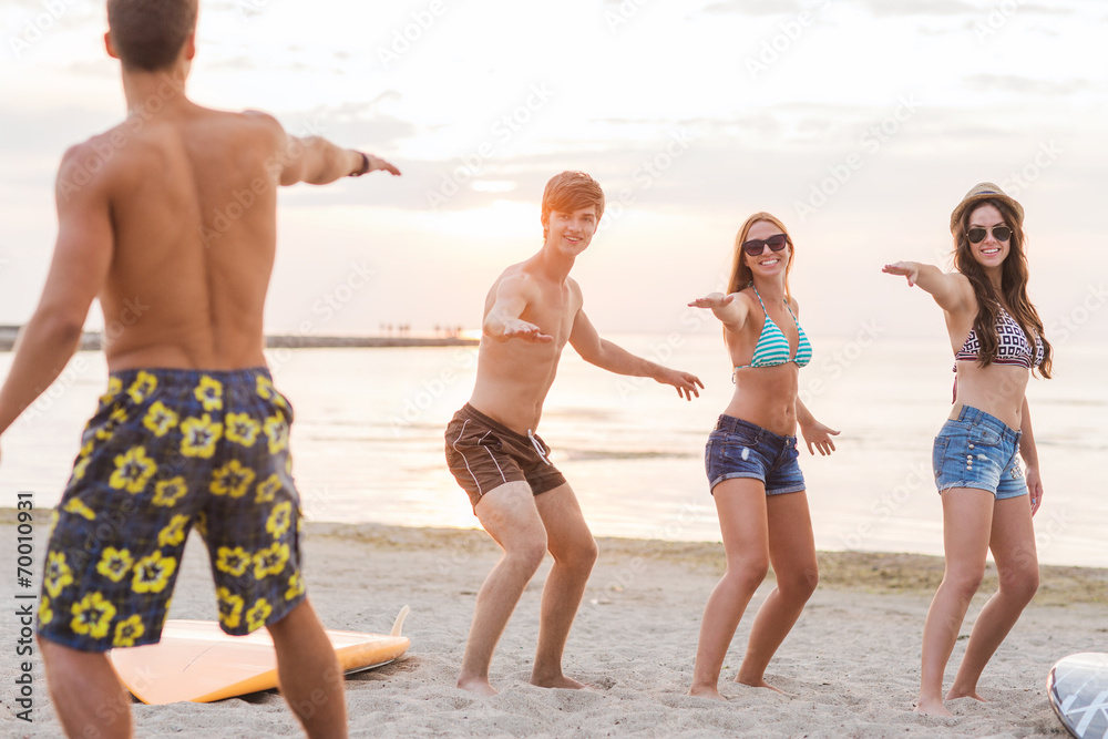 smiling friends in sunglasses with surfs on beach