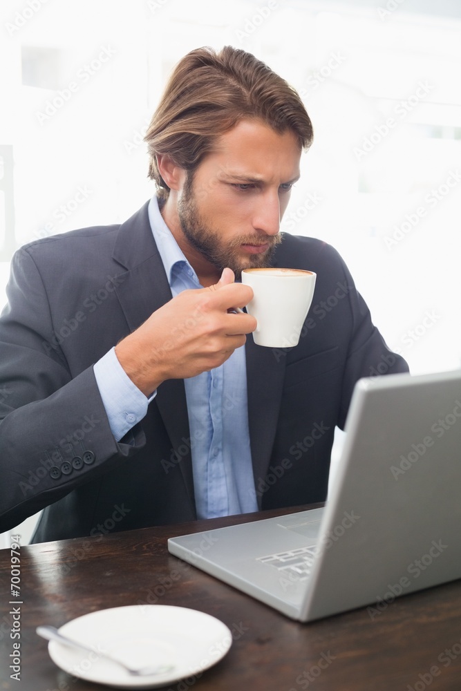 Businessman working on his laptop having coffee Businessman working on his laptop having coffee