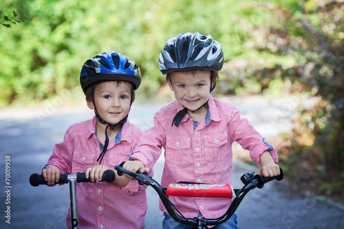 Portrait of two boys in the park, riding bike and scooter