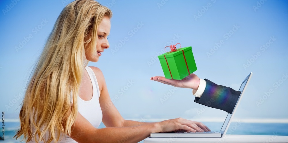 Composite image of pretty blonde using her laptop at the beach Composite image of pretty blonde using her laptop at the beach