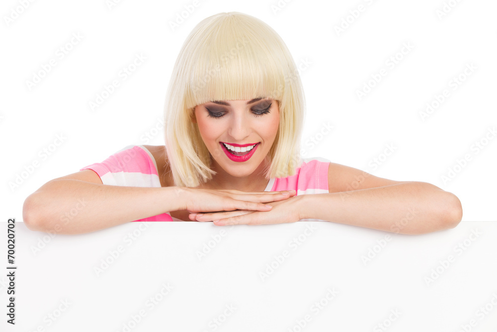 Smiling blonde leaning on a banner and reading Smiling blonde leaning on a banner and reading