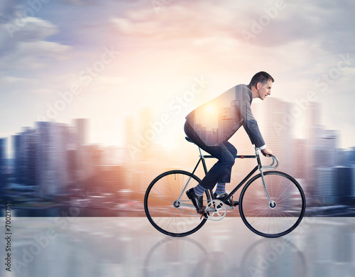 Double exposure of man on a bicycle and city photo