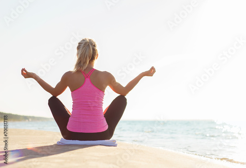 Silhouette of healthy woman practicing yoga on the beach