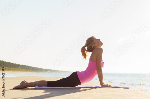 Young healthy and fit woman practicing yoga on the beach