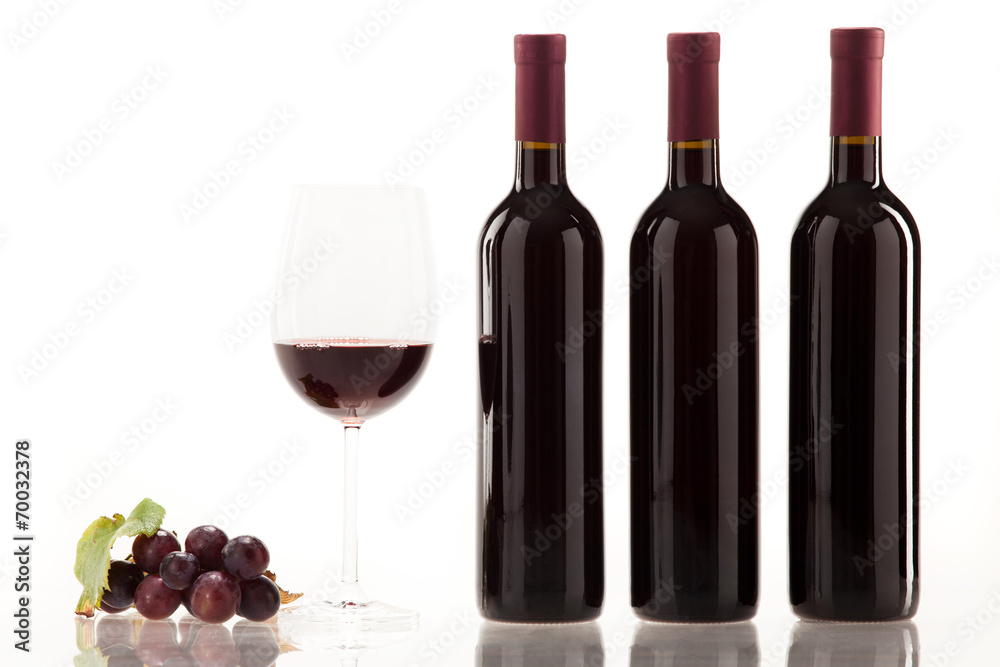 Obraz premium Rotwein im Glas mit Frucht, Blätter und Weinflasche