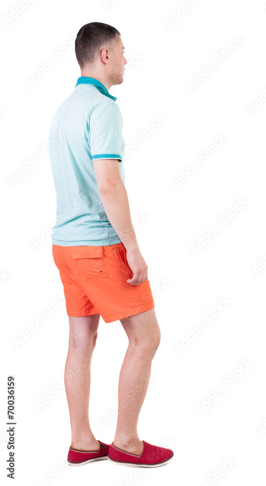 Back view of going  handsome man in shorts.  walking young guy