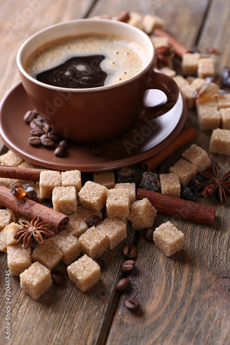 Brown sugar, spices and cup of coffee on wooden background