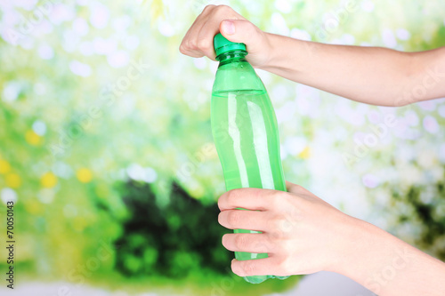 Hand opening bottle with sweet water on natural background