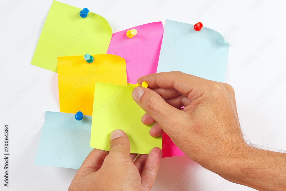 Hand attaches orange sticker on a white message board