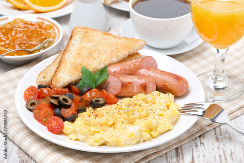 scramble eggs with tomatoes, sausage and toast on a plate