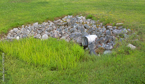 Storm culvert surrounded by rocks and grass photo