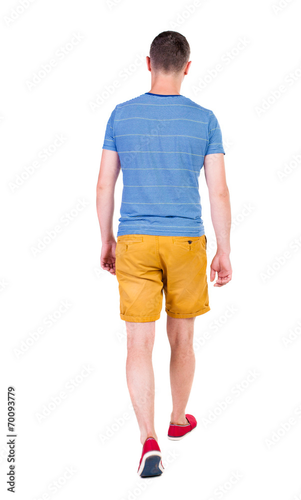 Back view of going  handsome man in shorts.  walking young guy