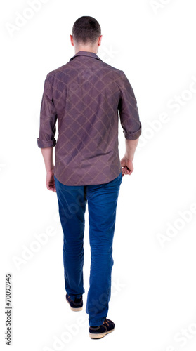 Back view of going handsome man in jeans and a shirt.