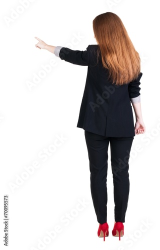 Back view of young redhead business woman pointing at wal