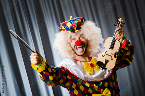 Funny clown plyaing violin against curtain photo