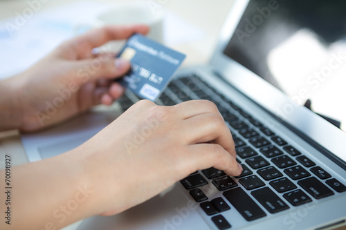 Hands holding a credit card and using laptop computer for online