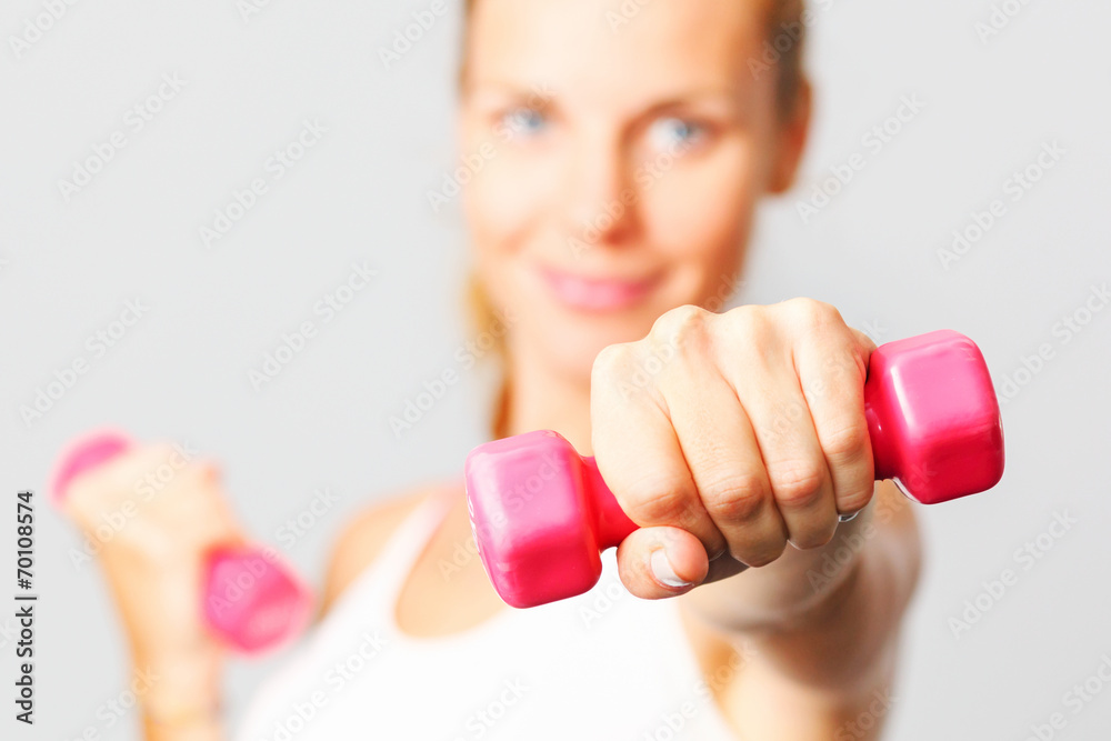Young woman with dumbbells in her hands.